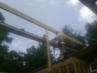 Carpenter setting a ridge beam over a new addition frame — Ice Dam Removal by Roofing Brothers in Burtrum