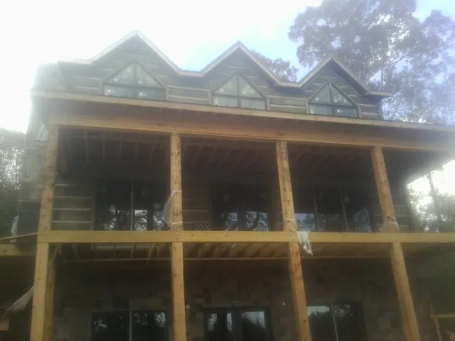 Dormers and porch framing on a large log home under construction — Roof Coating work by our crew in Burtrum