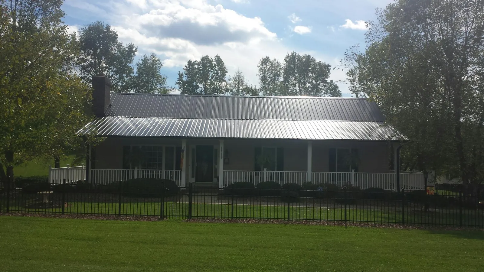Gray metal roof on a brick ranch with a full width front porch — Gutter Guard Installation work by our crew in Burtrum