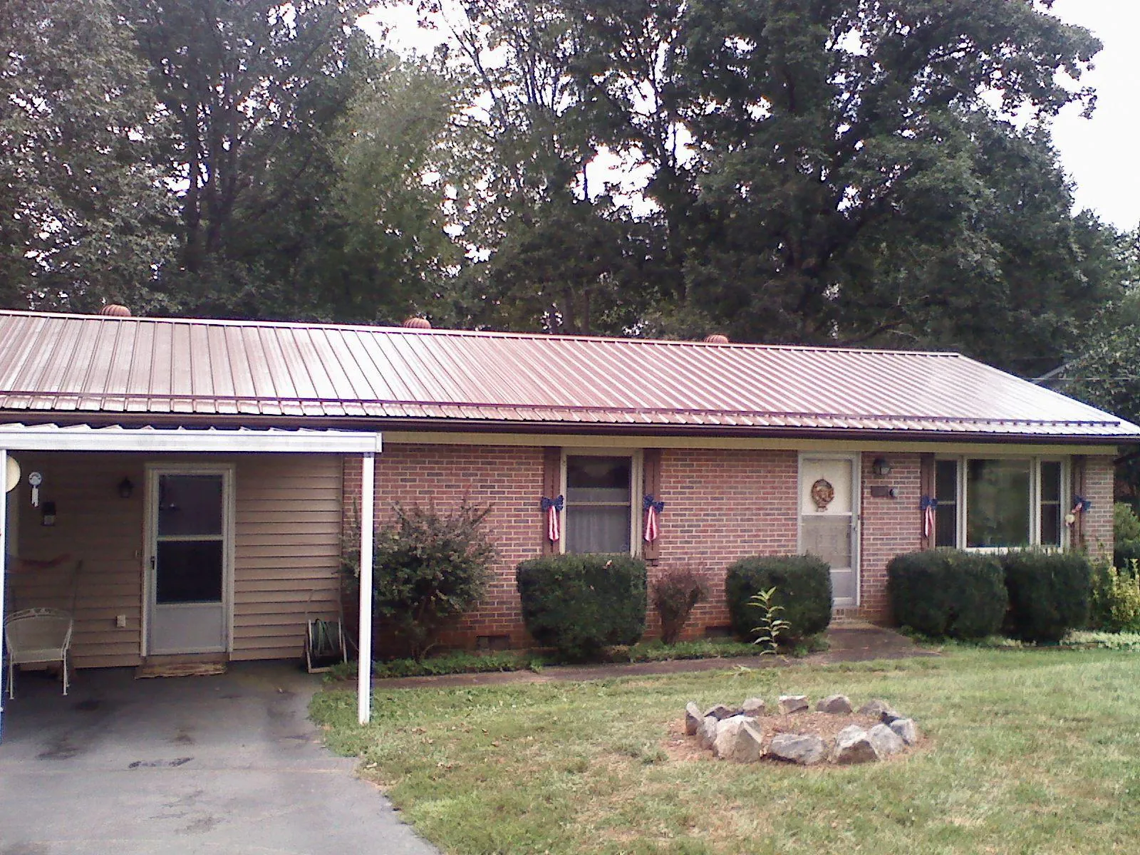Bronze metal roof and carport on a brick ranch home — Roof Repair work by our crew in Burtrum