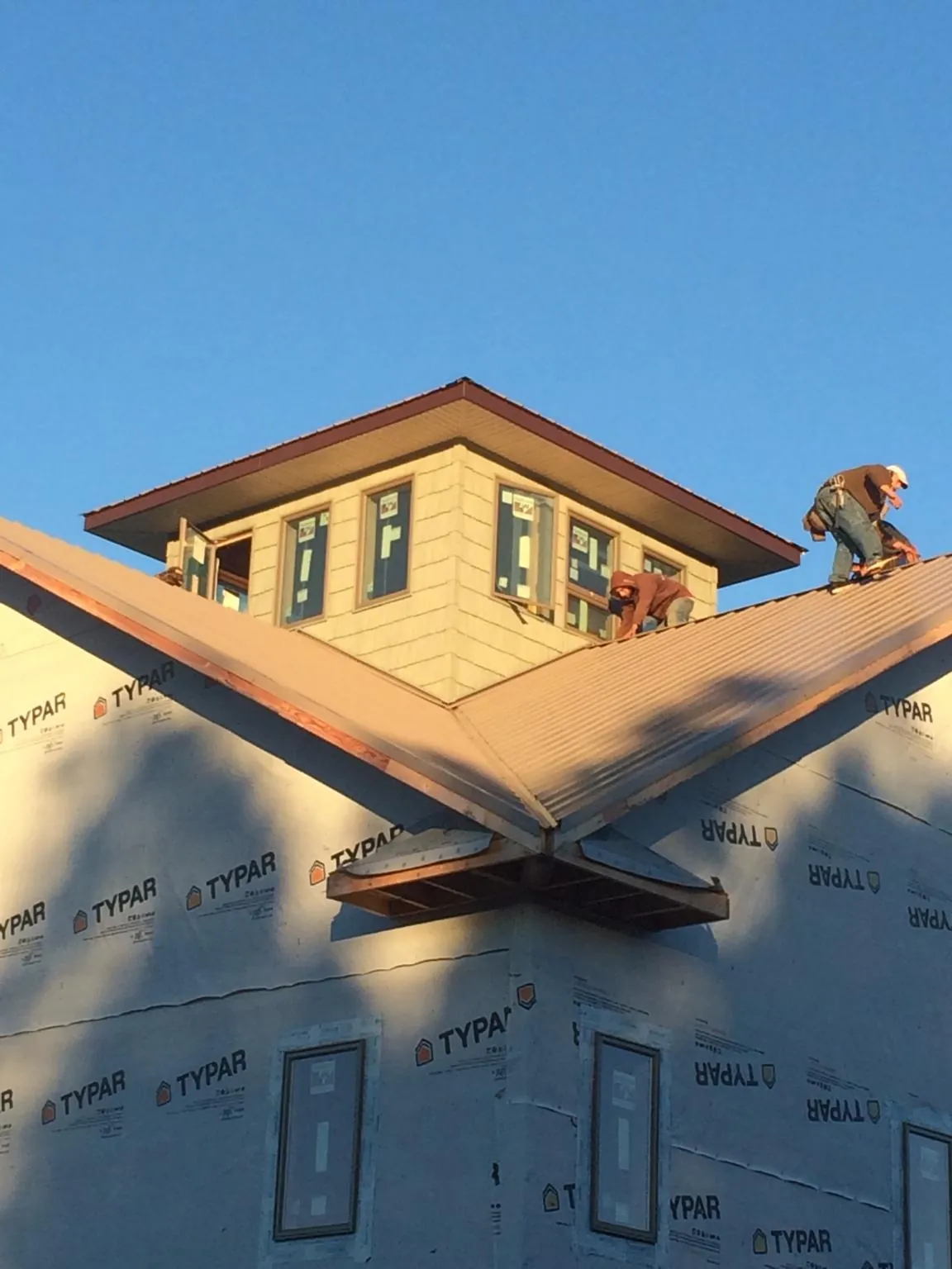 Roofers working around a rooftop cupola on a new metal roof at sunset — Roof Waterproofing in Burtrum by Roofing Brothers